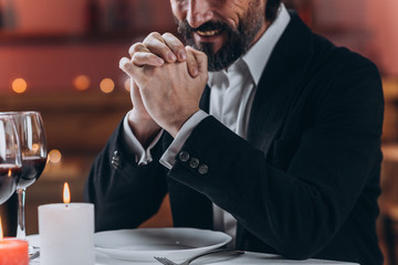 Lonely bearded man in a suit sits alone at a table in a restaurant close-up
