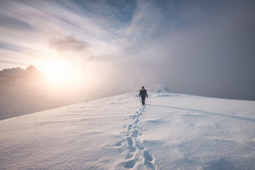 Man mountaineer walking with snow footprint on peak ridge - Powered by Adobe