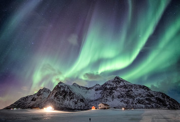 Aurora borealis with starry over snow mountain range with illumination house in Flakstad, Lofoten islands, Norway © Mumemories