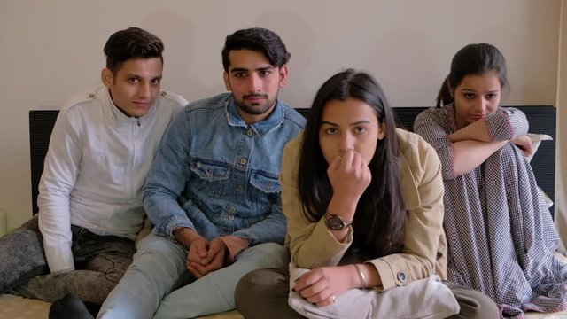 Friends focused and watching a drama cinema film on the television as of the guys has tears rolling down his eyes with emotions