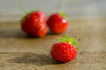 three strawberries on a wooden table