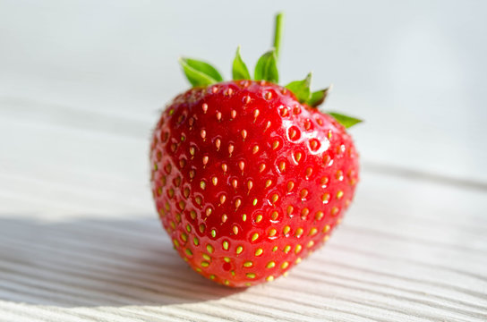 one strawberry on a wooden table