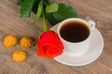 wooden table with coffee cup, cookies and red rose