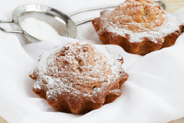 Two fresh homemade cupcakes with raisins sprinkled with powdered sugar