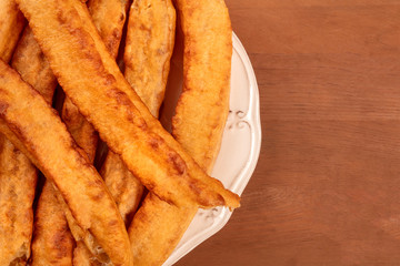 A closeup of traditional Spanish porras, a typical Madrid Sunday breakfast, shot from the top on a dark rustic wooden background with a place for text