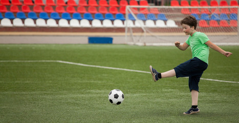 child run soccer (football) player. Boy with ball on green grass