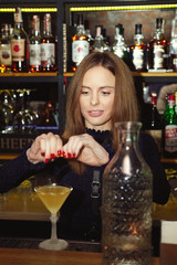 Professional bartender girl squeezing a orange peel in cocktail