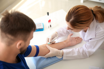 Fototapeta premium Female doctor drawing a blood sample of male patient in clinic