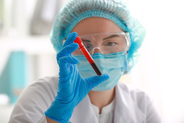 Naklejka premium Medical professional examining blood sample in test tube for laboratory analysis and disease diagnosis, the focus is on scientific investigation and medical testing procedures