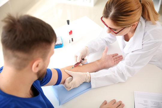 Female doctor drawing a blood sample of male patient in clinic