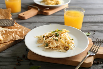 Plate with delicious pasta on wooden board