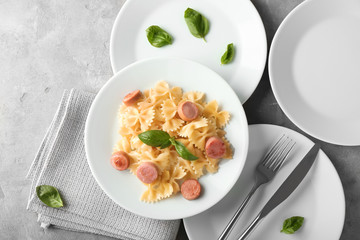 Plate with delicious pasta and sausage on grey table