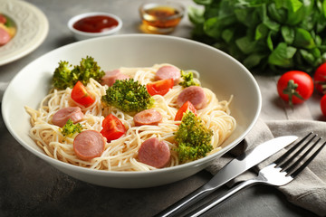 Plate with delicious pasta and sausage on grey table