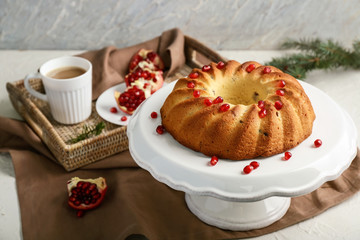 Stand with delicious Christmas cake and cup of coffee on white table