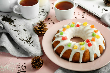 Plate with delicious Christmas cake and cups of tea on color table
