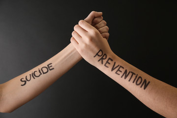 Female hands with text SUICIDE PREVENTION on dark background