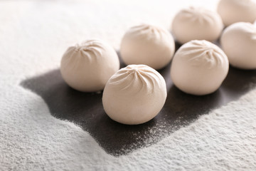 Raw Chinese dumplings and flour on table