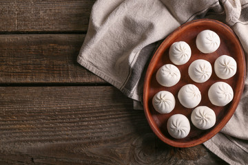 Plate with raw Chinese dumplings on wooden table