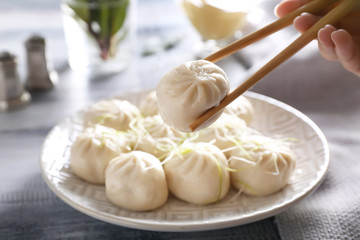Woman eating tasty Chinese dumplings with chopsticks