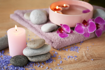 Fototapeta na wymiar Beautiful spa composition with burning candle and stones on wooden table