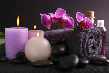 Beautiful spa composition with candles, stones and bath towel on dark table