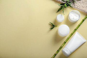 Jars and tube with body cream on color background