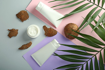 Cream, palm leaves and coconut on color background
