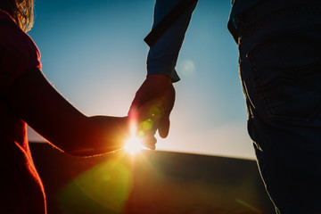 silhouette of little girl and dad holding hands at sunset, parenting
