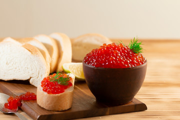 red caviar in a ceramic dish on a wooden background in a rustic style with space for text