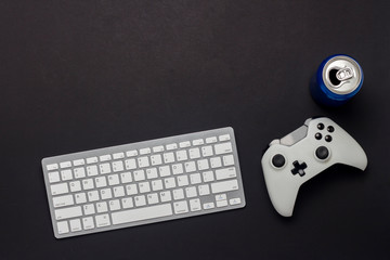 Keyboard, gamepad and a can of drink on a black background. The concept of the game on the PC, gaming, console. Flat lay, top view.