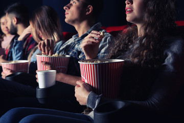 Friends eating popcorn while watching movie in cinema