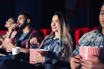 Friends eating popcorn while watching movie in cinema