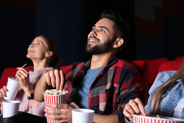 Friends eating popcorn while watching movie in cinema