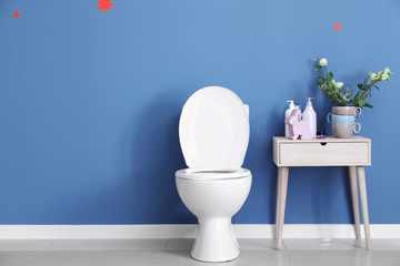 Modern ceramic toilet bowl near color wall in restroom