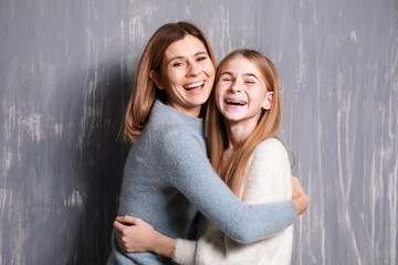Portrait of happy mother and daughter on grey background