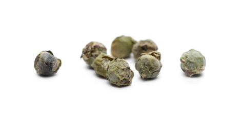 Dry green pepper pile, macro peppercorn isolated on white