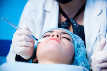 Fototapeta premium Master in massage center applying mask with brush on face of relaxing woman.