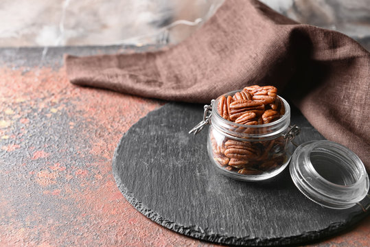 Jar with tasty pecan nuts on table