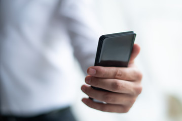Closeup of business man holding smartphone. Person using holding smartphone. Communication concept. Cropped view.