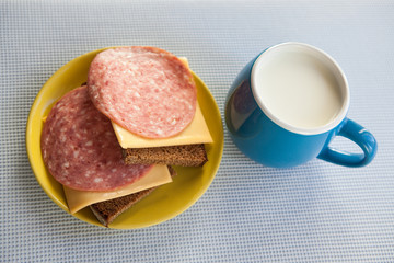 Milk and bread with salami on the table in the morning