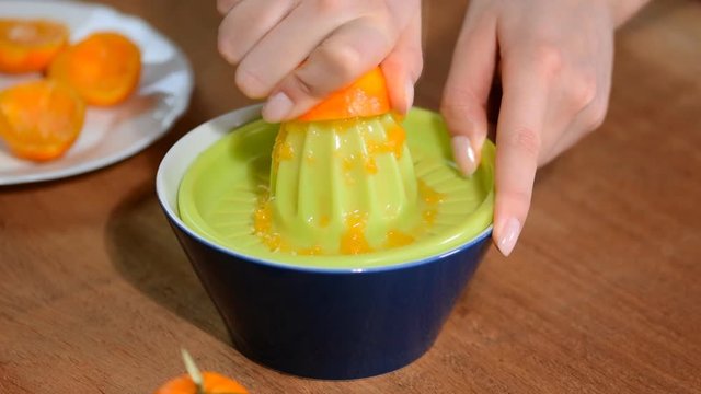 Female hand squeeze the juice out of tangerines.