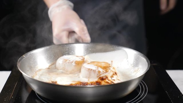 Cooking seafood in restaurant. Professional chef stirring frying pan with scallops and vegetables in cream dressing. Slow motion. hd