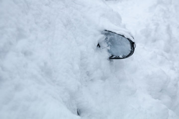 parkendes Auto unter dem Schnee begraben, nur der Spiegel schaut heraus