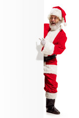 Happy surprised Santa Claus pointing on blank advertisement banner background with copy space. Smiling senior man showing at white blank of empty poster