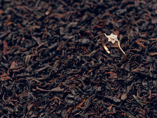 background of black tea leaves. precious ring. decorations.