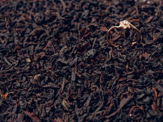 background of black tea leaves. precious ring. decorations.