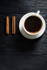 cup of coffee and cinnamon on wooden table