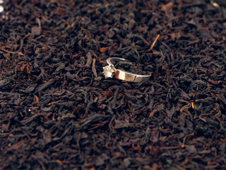background of black tea leaves. precious ring. decorations.