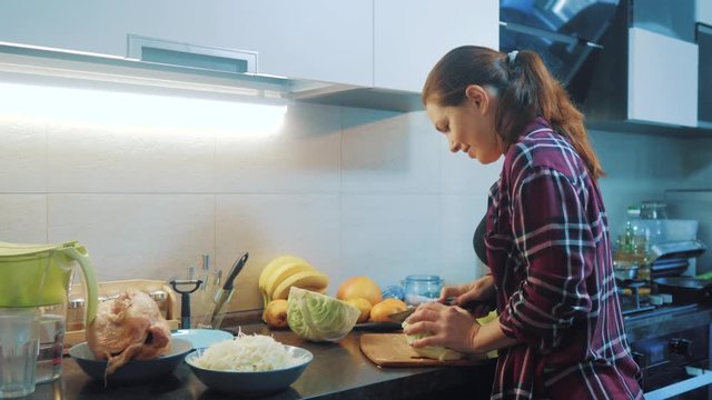 woman in the kitchen preparing lifestyle a meal concept. girl in the kitchen cuts cabbage with a knife. cook vegetarian food healthy food. girl at home in the kitchen slow motion video