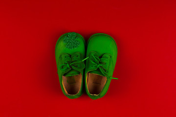green baby shoes isolated on red background